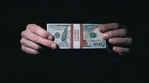 Pilha de 10000 dólares americanos no pacote em mãos masculinas em fundo preto — Vídeo de Stock