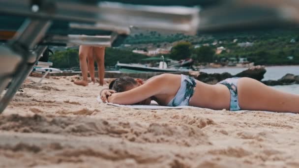 Нижче наведений погляд на молоду дівчинку, яка бреше і купається на піщаному пляжі. — стокове відео