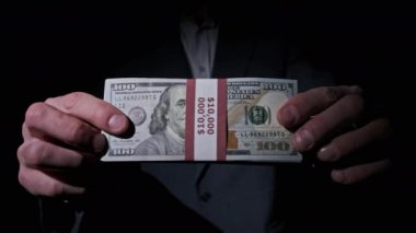 Takım Elbiseli İşadamı Siyah Arkaplanda 10000 Amerikan Doları Yığını Gösteriyor
