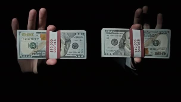 Deux piles de 10000 dollars américains faisceaux en mains masculines sur fond noir — Video