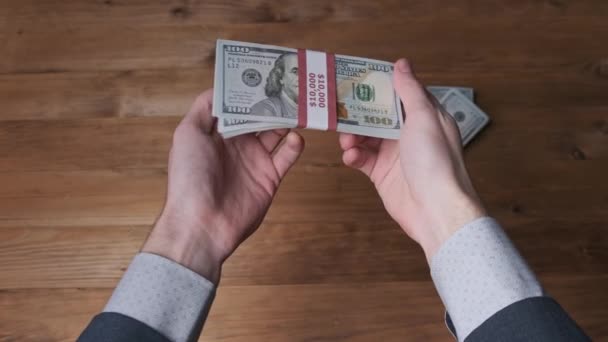 Stack of 10000 American Dollars Banknotes in Male Hands over Wooden Background — Stock Video