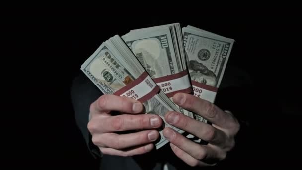 Três pilhas de 10000 dólares americanos pacotes em mãos masculinas em fundo preto — Vídeo de Stock