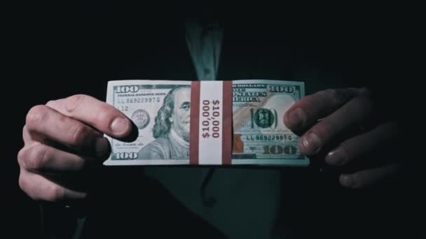 Takım Elbiseli İşadamı Siyah Arkaplanda 10000 Amerikan Doları Yığını Gösteriyor — Stok video