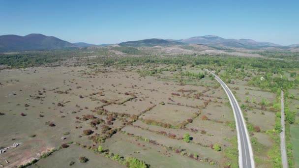 Vista aérea Camino de asfalto vacío en la meseta entre campos verdes, Highland Way — Vídeos de Stock