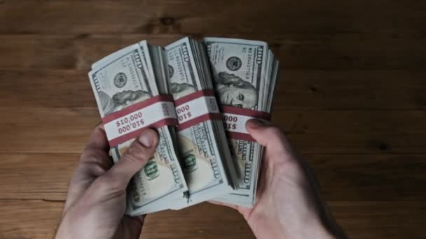 Мужские руки переворачивая стеки 10000 долларов счета на деревянном фоне, медленное движение — стоковое видео