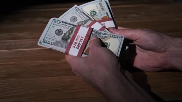 Mannelijke handen houden drie stapels van 10000 US Dollar Facturen op Houten Achtergrond — Stockvideo