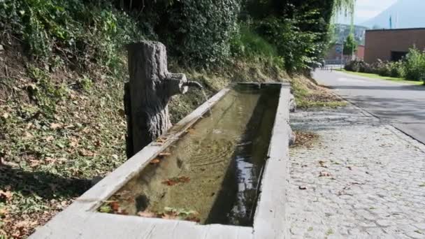 Água da montanha derrama de uma torneira em um recipiente de madeira na rua Liechtenstein — Vídeo de Stock