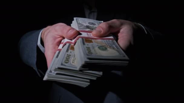 Empresário de terno mostra pilha de 10000 dólares americanos em fundo preto — Vídeo de Stock