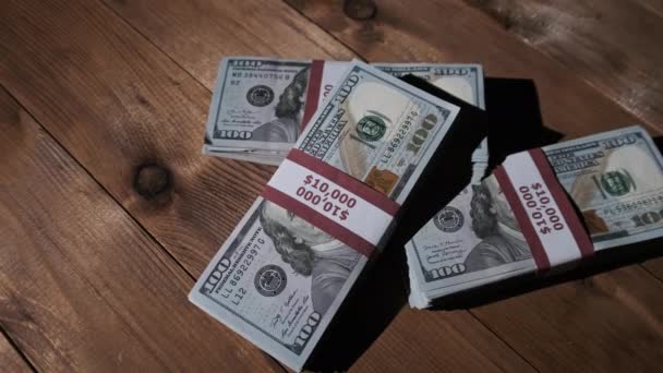 Tres pilas de billetes de 10000 dólares americanos en paquetes yacen sobre una mesa de madera — Vídeo de stock