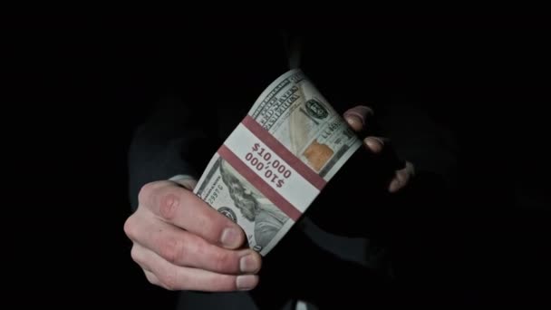 Pila de 10000 dólares americanos en paquete en manos masculinas sobre fondo negro — Vídeo de stock