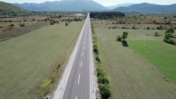 Prázdná asfaltová cesta na náhorní plošině mezi zelenými poli, letecký pohled na vysočinu — Stock video