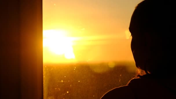 Silhouette of a Young Woman Looking Out the Window at Sunset, Slow Motion — Stock Video