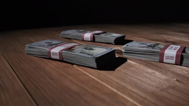 Três pilhas de 10000 dólares americanos Notas em pacotes mentem na mesa de madeira — Vídeo de Stock