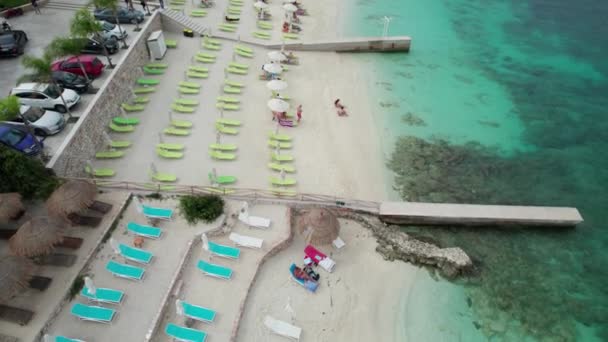 Vista aérea Azure Beach com espreguiçadeiras vazias, costa balcânica Mar Jónico Albânia — Vídeo de Stock