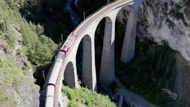Αεροφωτογραφία κινούμενου κόκκινου τρένου κατά μήκος του Landwasser Viaduct στις Ελβετικές Άλπεις — Αρχείο Βίντεο