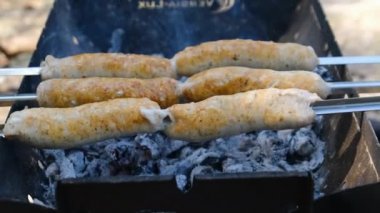 Sosisler portatif ızgarada pişiriliyor. Kapatın, barbekü.