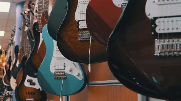 Lote de guitarras elétricas multicoloridas penduradas em uma loja de música, loja de guitarra — Vídeo de Stock