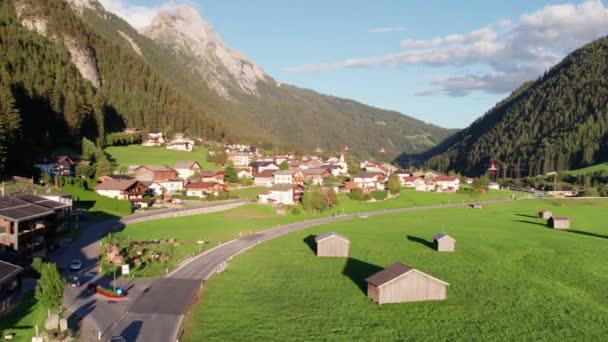 Uitzicht vanuit de lucht op een Oostenrijks dorp in een groen bergdal bij zonsondergang, Alpen — Stockvideo