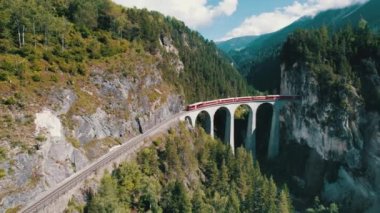 İsviçre Alplerindeki Landwasser Viaduct boyunca ilerleyen bir Kızıl Trenin Hava Görüntüsü