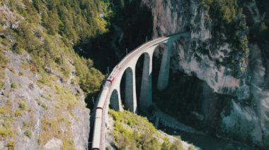 İsviçre Alplerindeki Landwasser Viaduct boyunca ilerleyen bir Kızıl Trenin Hava Görüntüsü