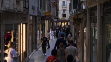 Venedik 'teki hediyelik eşya dükkanlarının yakınındaki dar bir sokakta bir kalabalık yürüyor.