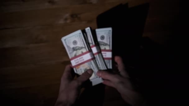Male Hands Hold Three Stacks of 10000 US Dollar Bills on Wooden Background — Stock Video