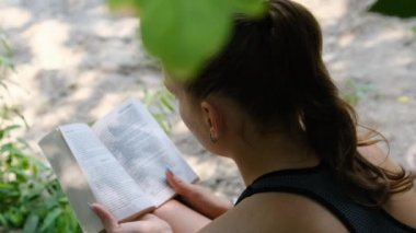 Genç Kadın, Yaz Gününde Doğada Çimlerin Üzerinde Oturan Bir Kitap Okuyor