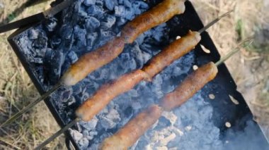 Dikey video, Sausages on Skewers Portable Grill Outdoor 'da pişiriliyor.