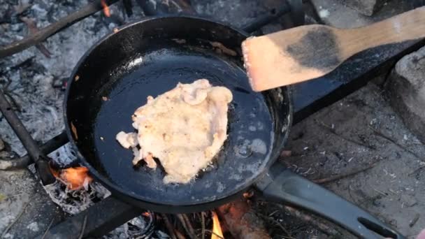Жареная свиная отбивная в масле в сковороде над огнем на открытом воздухе, приготовление жирного мяса — стоковое видео