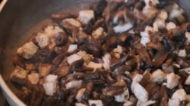 Mantarlar ev mutfağında bir tavada kızartılıyor, Julienne mantarları pişiriliyor.