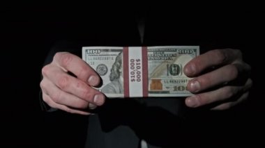 Takım Elbiseli İşadamı Siyah Arkaplanda 10000 Amerikan Doları Yığını Gösteriyor
