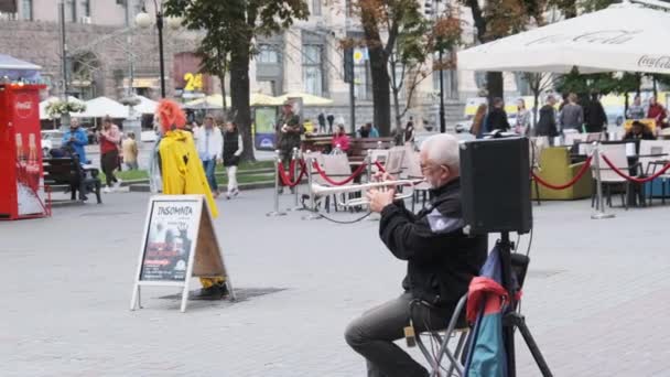 Músico de rua tocando trompete enquanto sentado em uma cadeira na calçada — Vídeo de Stock