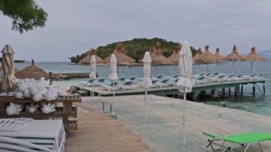 Turkuaz Denizi 'ndeki Sahilde İskeledeki Saman Şemsiyeli Boş Güneş Salonları