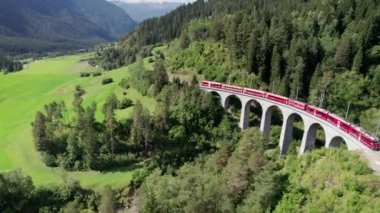 İsviçre Alplerindeki Landwasser Viaduct boyunca ilerleyen bir Kızıl Trenin Hava Görüntüsü