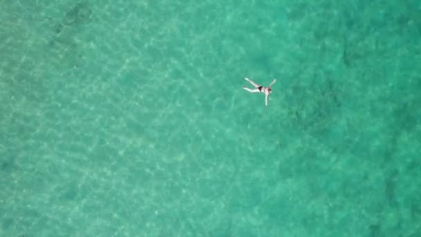 Vista aérea de cima para baixo da mulher nada em água cristalina em um mar transparente — Vídeo de Stock