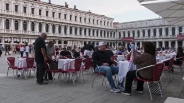 Turistler St. Marks Meydanı 'ndaki restoran ve kafelerin masalarında oturuyorlar.