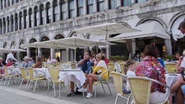 Turistler St. Marks Meydanı 'ndaki restoran ve kafelerin masalarında oturuyorlar.