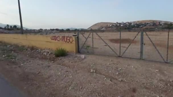 POV Biker monta por Muddy Garbage Road en Albania con edificios destruidos — Vídeos de Stock