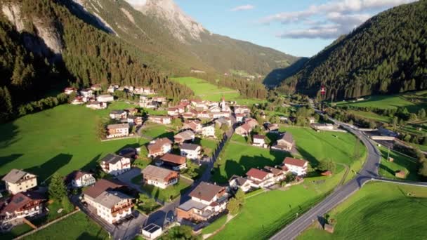 Flygfoto över en österrikisk by i en grön bergsdal vid solnedgången, Alperna — Stockvideo