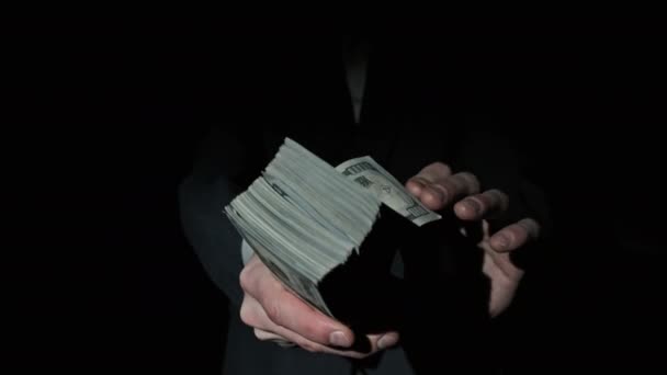 Tres pilas de 10000 dólares americanos paquetes en manos masculinas sobre fondo negro — Vídeo de stock