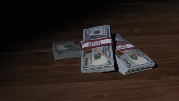 Három kötegben 10000 amerikai dollár bankjegyek csomagban feküdt a fából készült asztalon — Stock videók