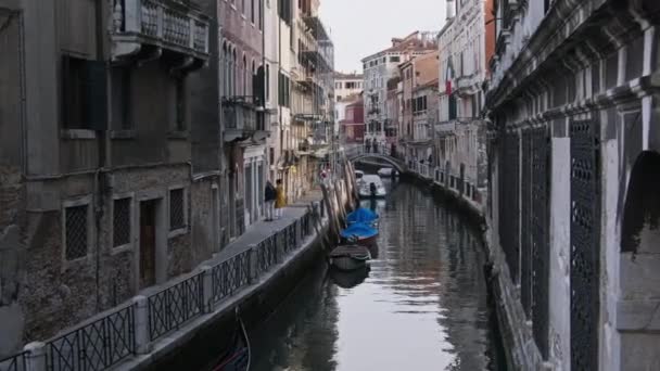 Вузькі канали Венеції з Гондолас припарковані на воді між барвистими будинками — стокове відео