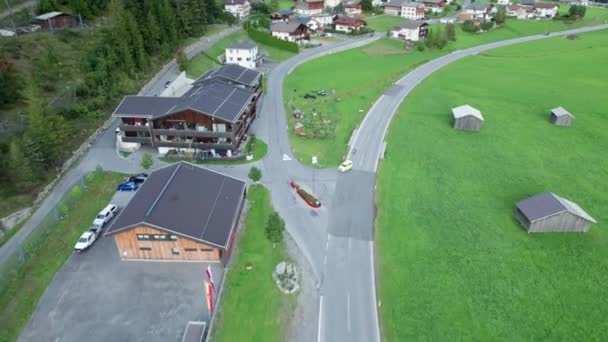 Road in Austrian Alp Valley Entre Campos Verdes e Casas de Madeira, Vista aérea — Vídeo de Stock