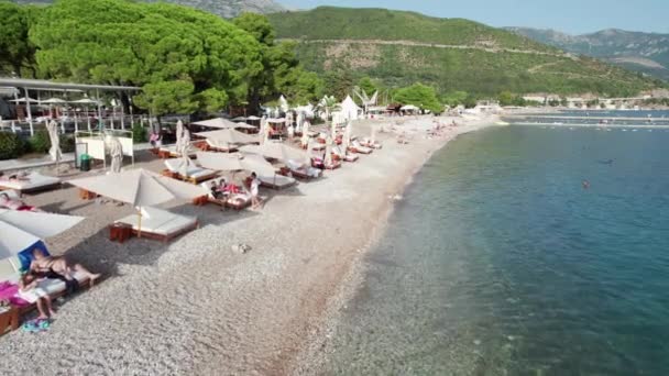Luchtfoto Budva Strand aan Zee met ligstoelen en mensen, Seashore Montenegro — Stockvideo