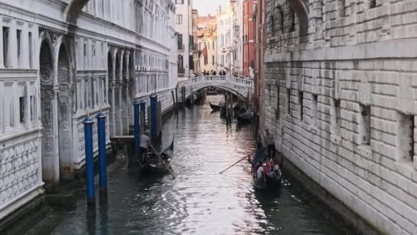 Вузькі канали Венеції з Гондоланом, що плавають на воді між барвистими будинками — стокове відео