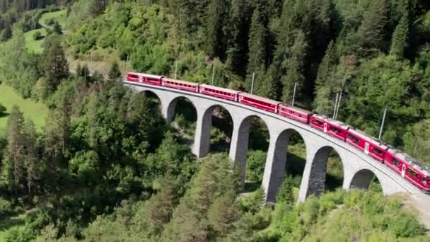 スイスアルプスのランドワッサー・ヴィアドュクトに沿って移動する赤い列車の空中ビュー — ストック動画