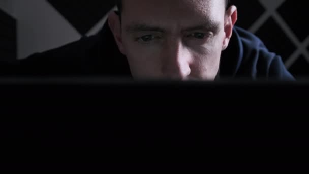 젊은 남자가 가정의 어두운 방에서 노트북 모니터 화면을 보고 있다 — 비디오