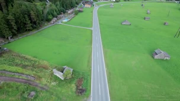 Пустая асфальтовая дорога в Австрии между зелеными полями в Альпах, вид с воздуха — стоковое видео