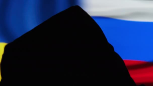 Silhouette of Man in Hood Against the Flags of Ukraine and Russia, Konfrontasi — Stok Video