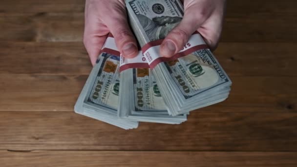 Férfi kéz flipping verem 10000 dollár számlák fa háttér, lassú mozgás — Stock videók